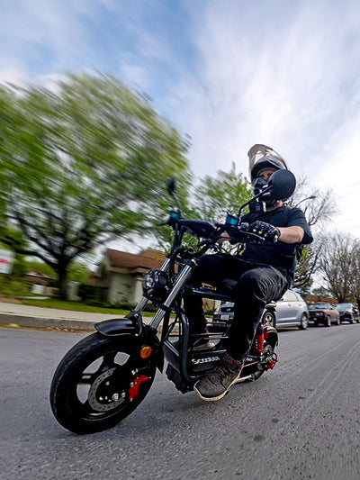 A rider wearing a helmet riding a black iScooter electric bike down a street.