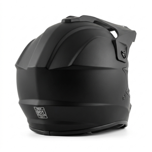 Rear-three-quarter view of a matte black full-face dirt bike helmet, featuring integrated top ventilation, a sun visor peak, and a prominent white DOT safety certification emblem printed at the bottom back center.