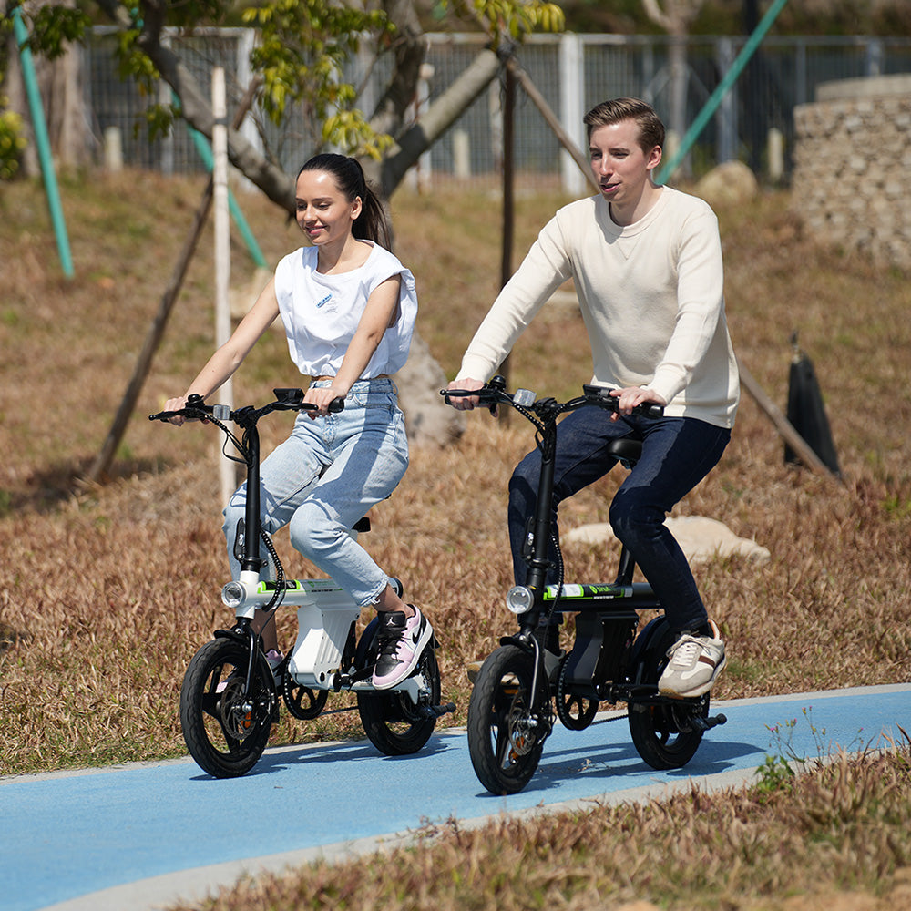 Side profile of a black folding electric bike with a step-through frame, compact wheels, rear hub motor, integrated battery, and adjustable seat displayed on a transparent background. The image showcases the bike's left side, highlighting its portable, urban commuter design.