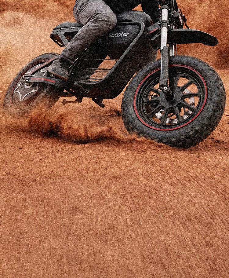 Close-up action shot of the iScooter DX5 Max electric bike riding through deep sand, with its oversized fat tires prominently displayed. The front tire churns through loose terrain while sand sprays outward, highlighting traction, stability, and all-terrain performance. The bike’s rugged frame and suspension are partially visible, emphasizing its off-road capability.