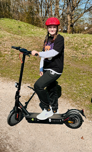 Person riding a scooter outdoors on a sunny day