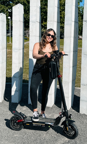 Woman standing next to a electric scooter in front of white columns