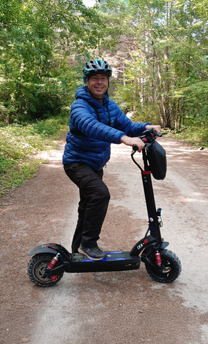 Person riding a scooter on a forest path