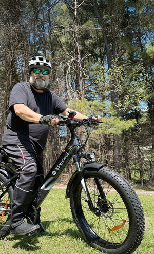 Man riding a black electric bike in a forested area