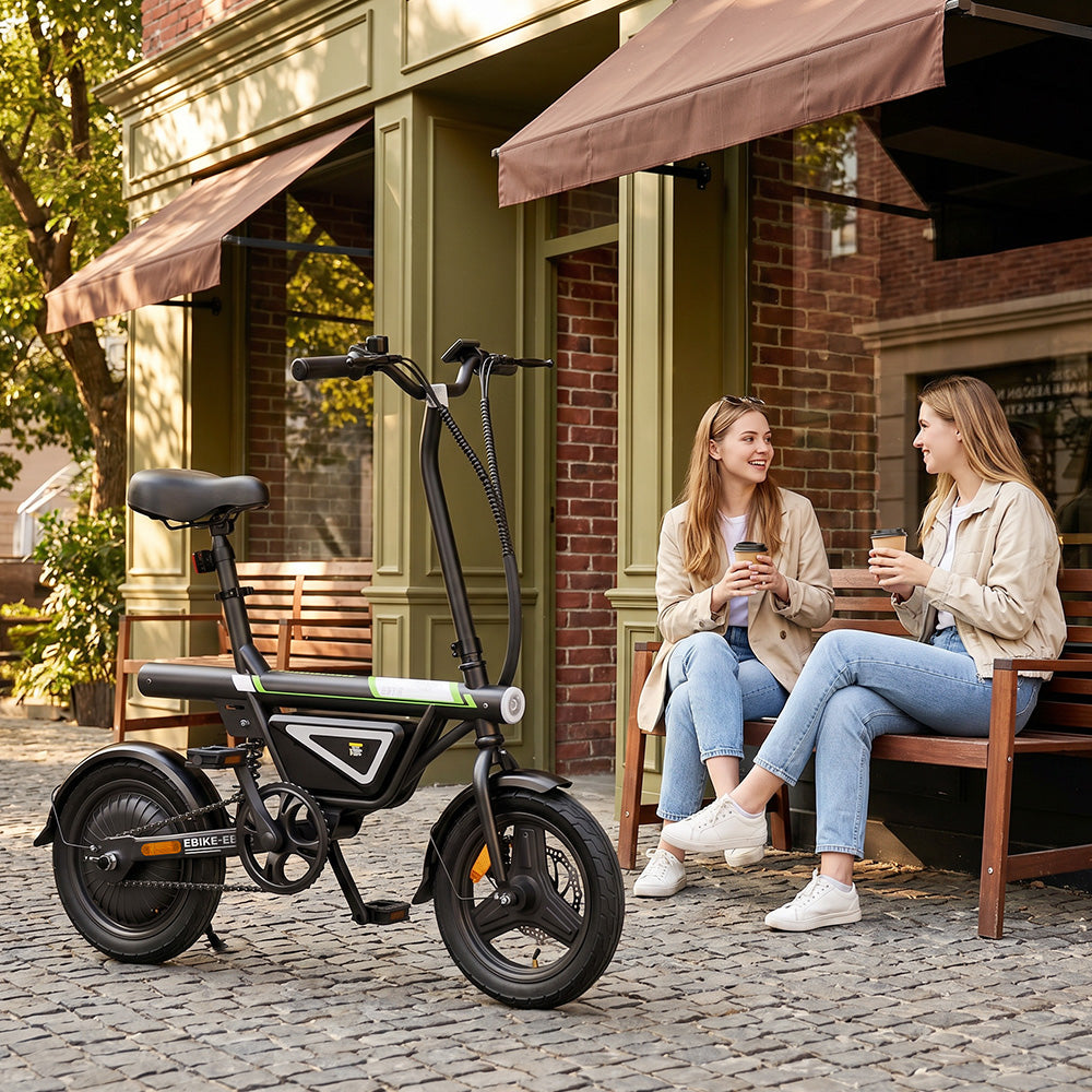 Electric bike with a compact frame, thick tires, and low step-through design parked on a cobblestone street outside a café, with two women sitting on a bench nearby, smiling and chatting while holding drinks.