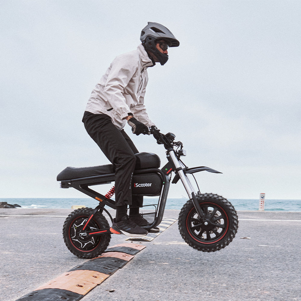 Rider crossing a road bump on the iScooter DX5 Max electric bike, demonstrating its suspension system, fat tires, and stable ride quality on varied terrain.