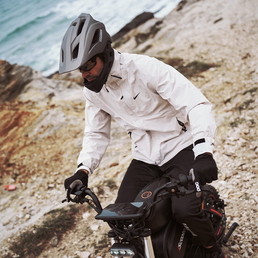 Rider on the iScooter DX5 Max electric bike navigating a rocky coastal trail, showcasing its all-terrain capability, stable handling, and adventure-ready design.