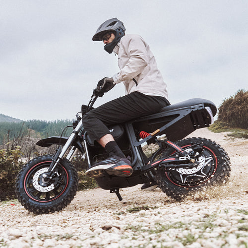 Rider navigating rough gravel terrain on the iScooter DX5 Max electric bike, showcasing its fat tires, rear suspension, and off-road performance in challenging outdoor conditions.