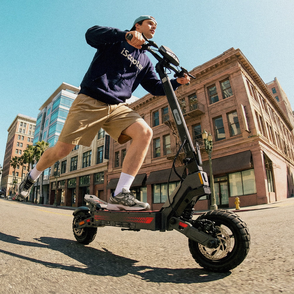 Rider commuting on an iScooter iF1 electric scooter through a city street, showcasing smooth urban mobility, durable off-road tires, and a powerful design against a backdrop of modern buildings and clear skies.