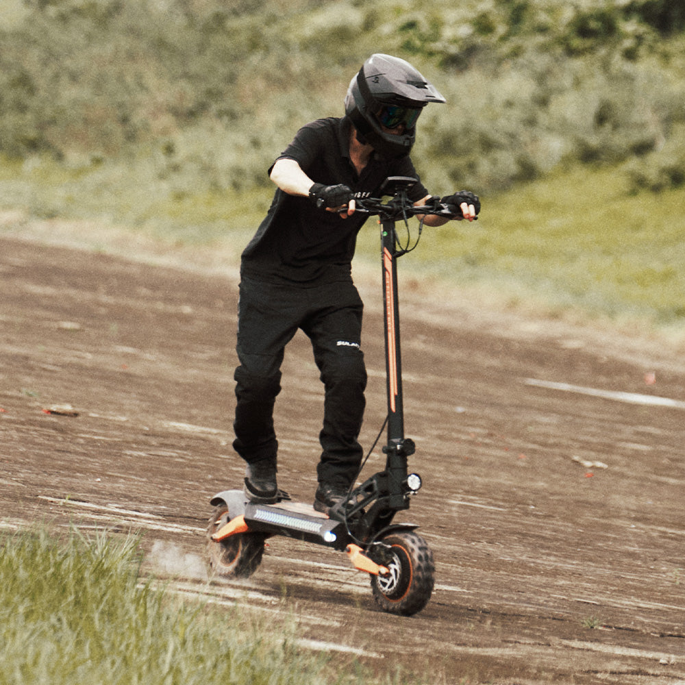 A rider in full gear leaning into a turn on an off-road electric scooter on a dirt track.