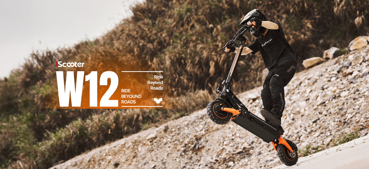 A rider in full protective gear riding an off-road iScooter W12 electric scooter up a steep incline.